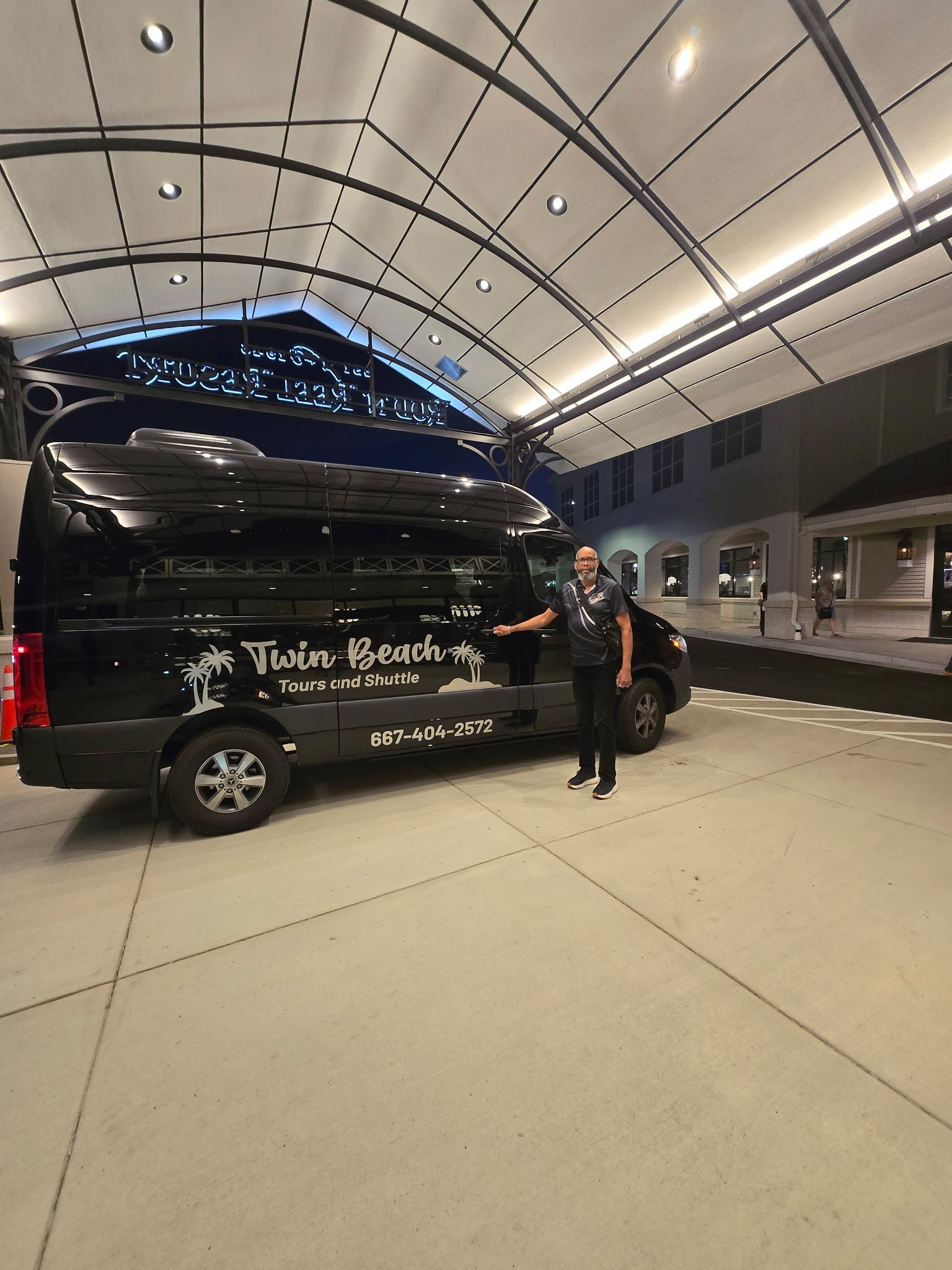 Twin Beach Tours black Mercedes Sprinter shuttle at a resort entrance at night